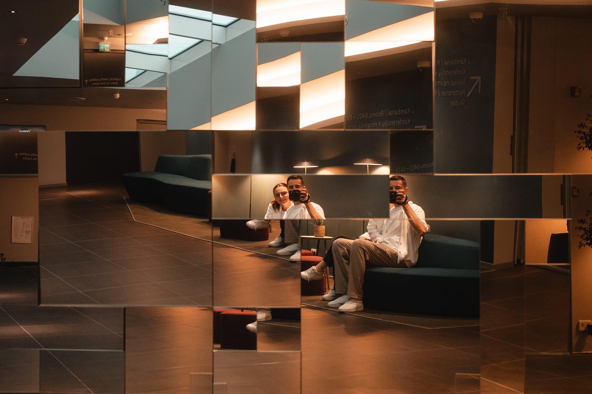 Two of the crew reflected in the lobby mirrors, both cameras up