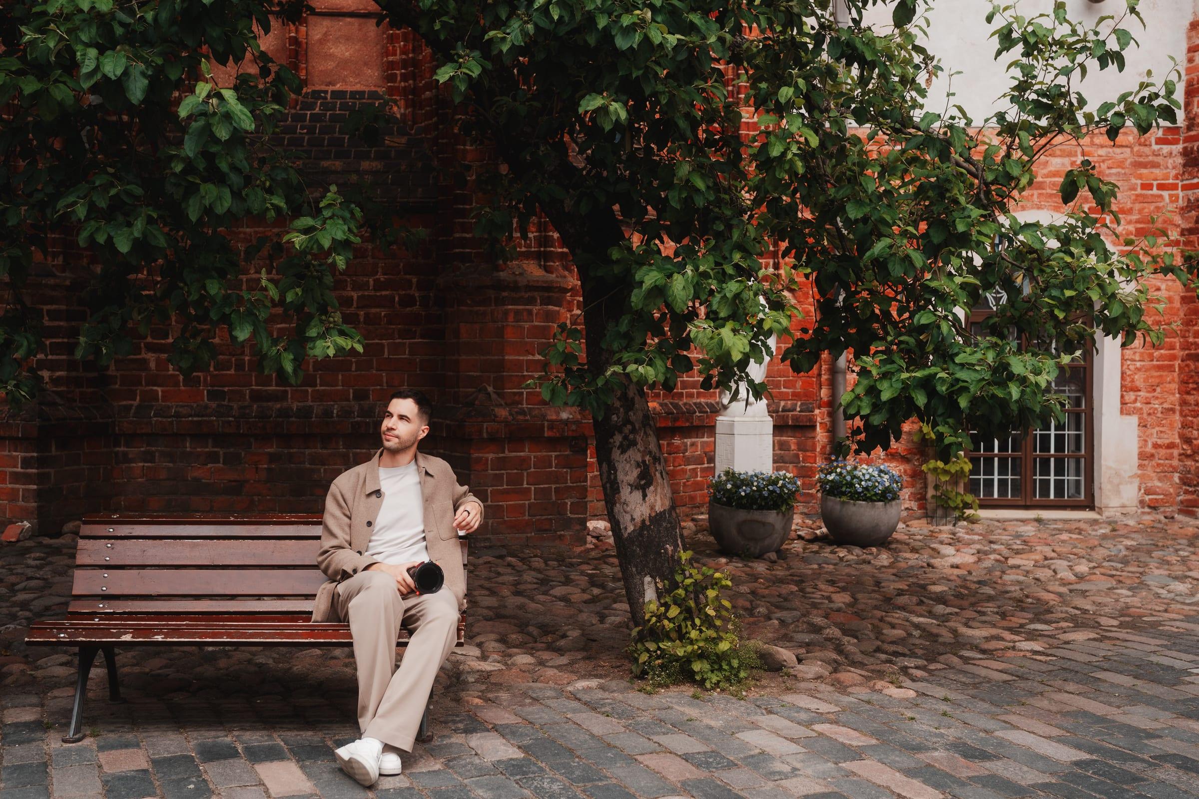 A break on a bench in a brick courtyard, a lens still in hand