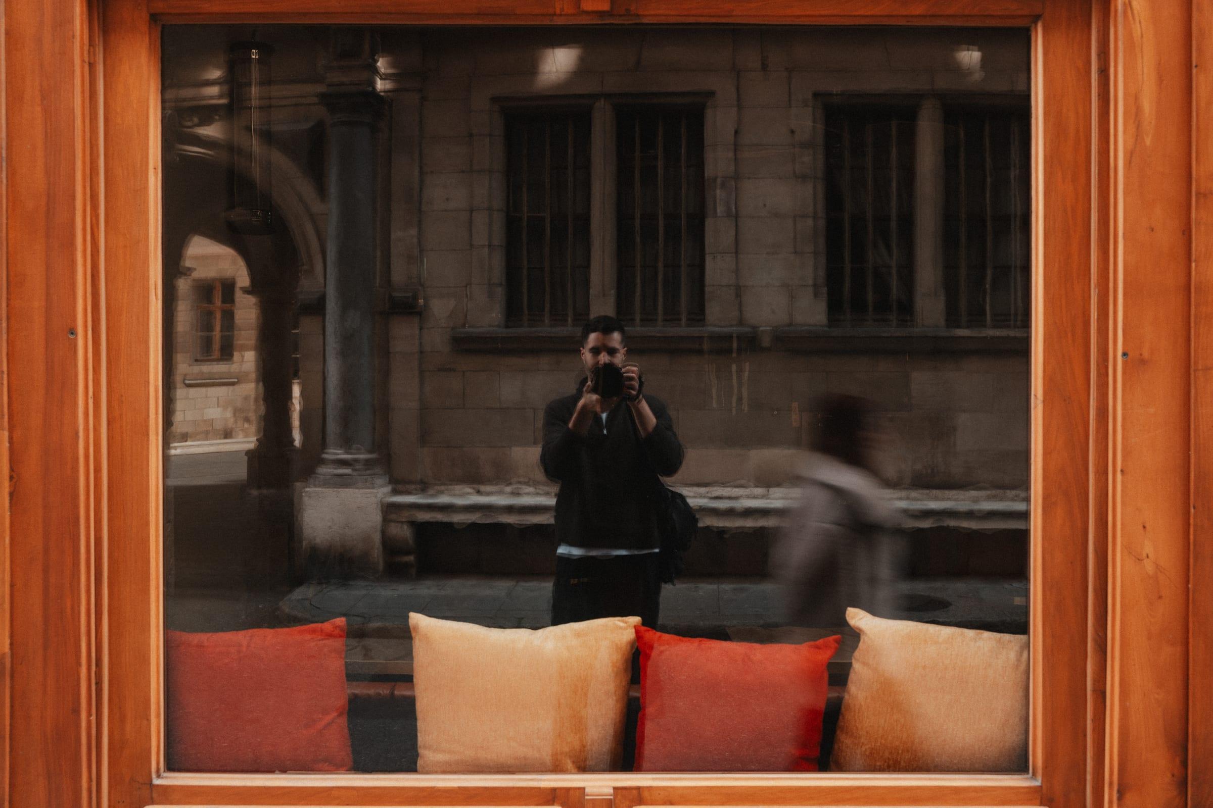 Caught in the restaurant window: the room and its cushions inside, the street reflected over it