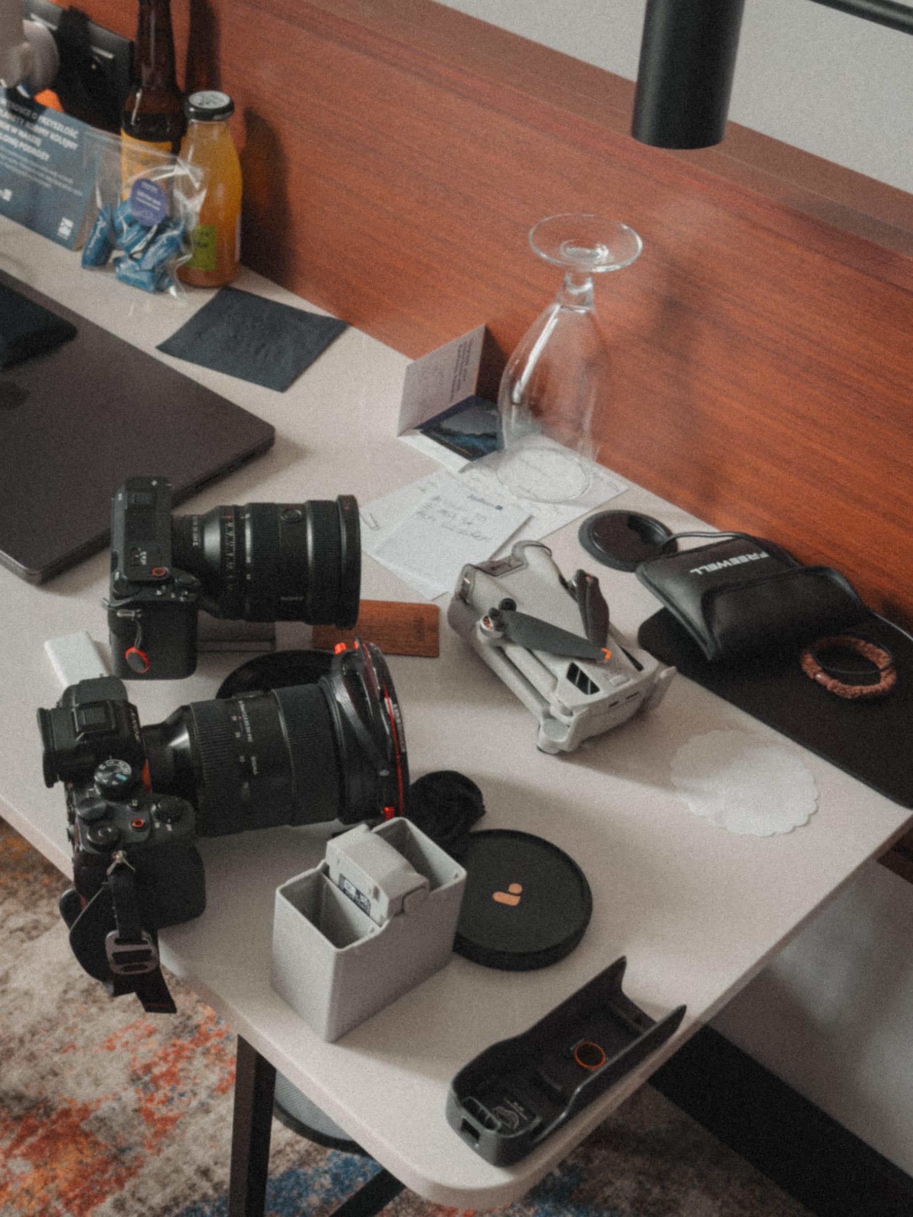 Two bodies, two lenses and a drone laid out across a hotel desk