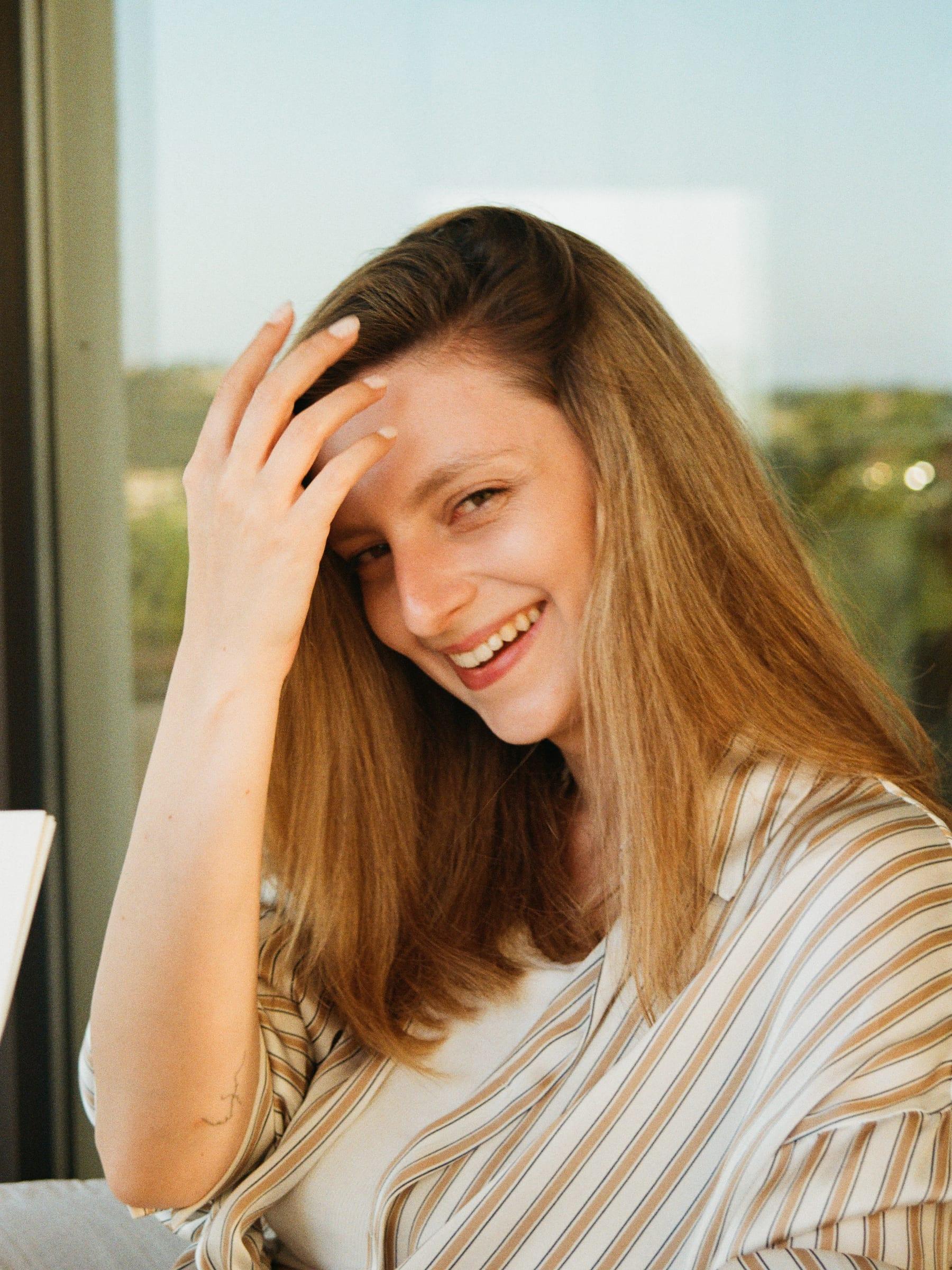 Laughing at the window with a hand pushed back through her hair