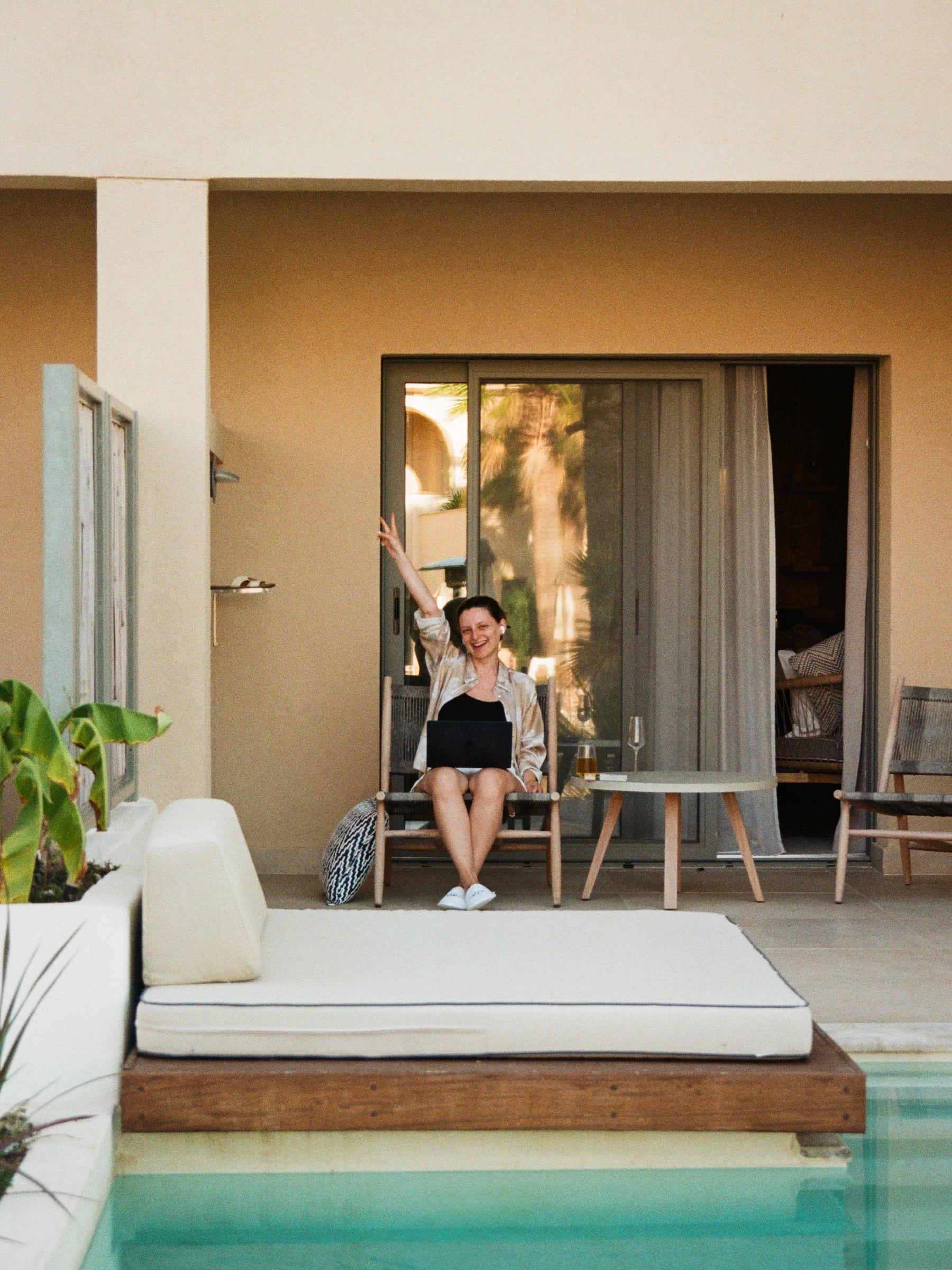Waving out of the doorway across the private pool