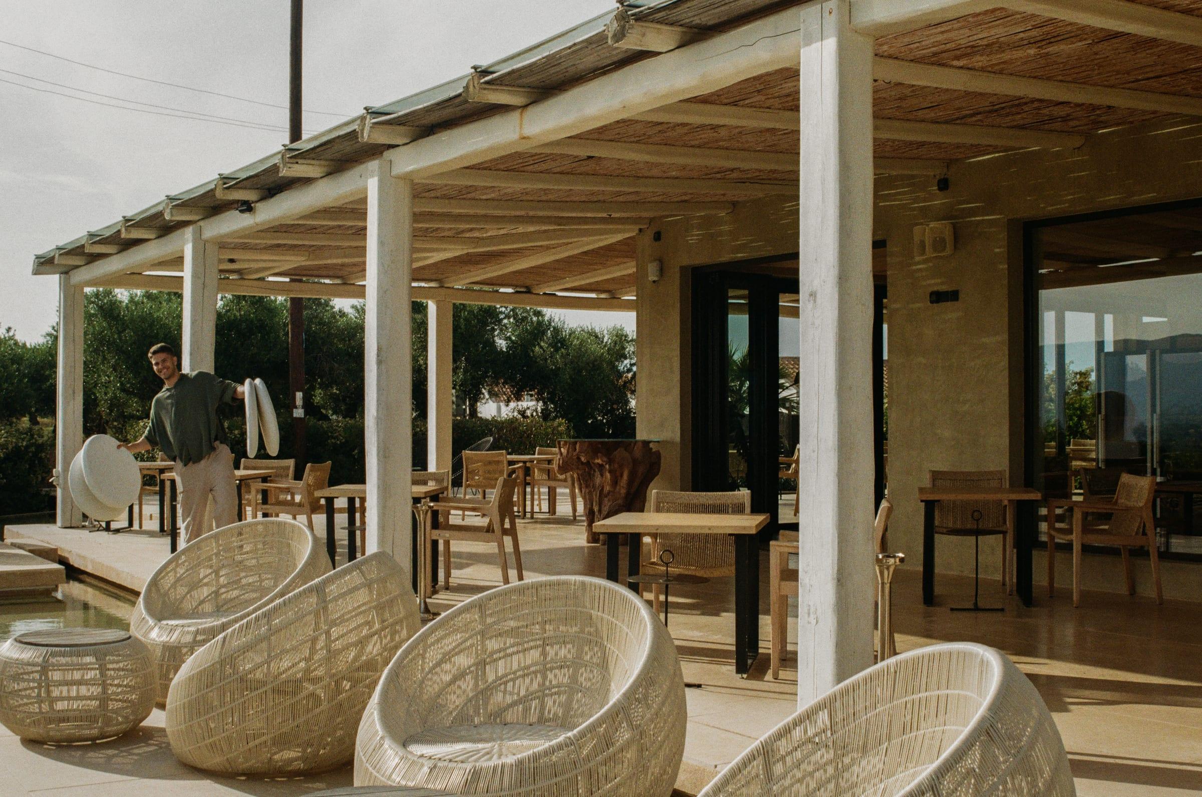 The terrace under the pergola, rattan chairs pulled around and nobody in them yet
